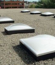 A rooftop with the top caps of VELUX Commercial Skylights facing upward.