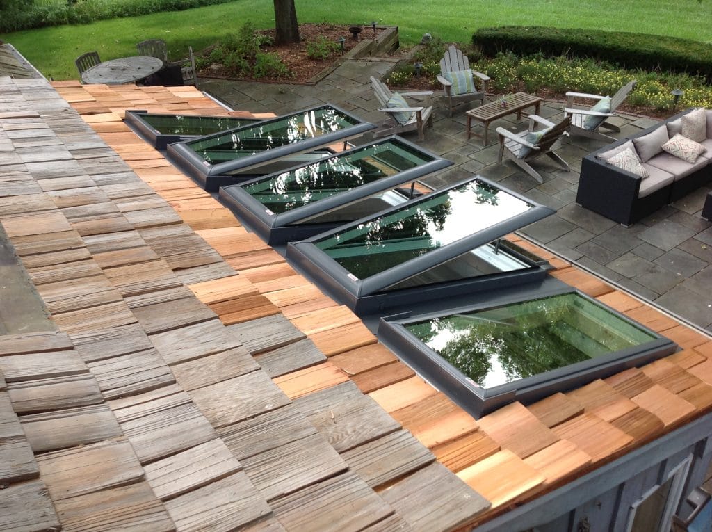 Five VELUX skylights installed on a roof by Wisconsin Sunlight Solutions with three positioned. upward for ventilation.
