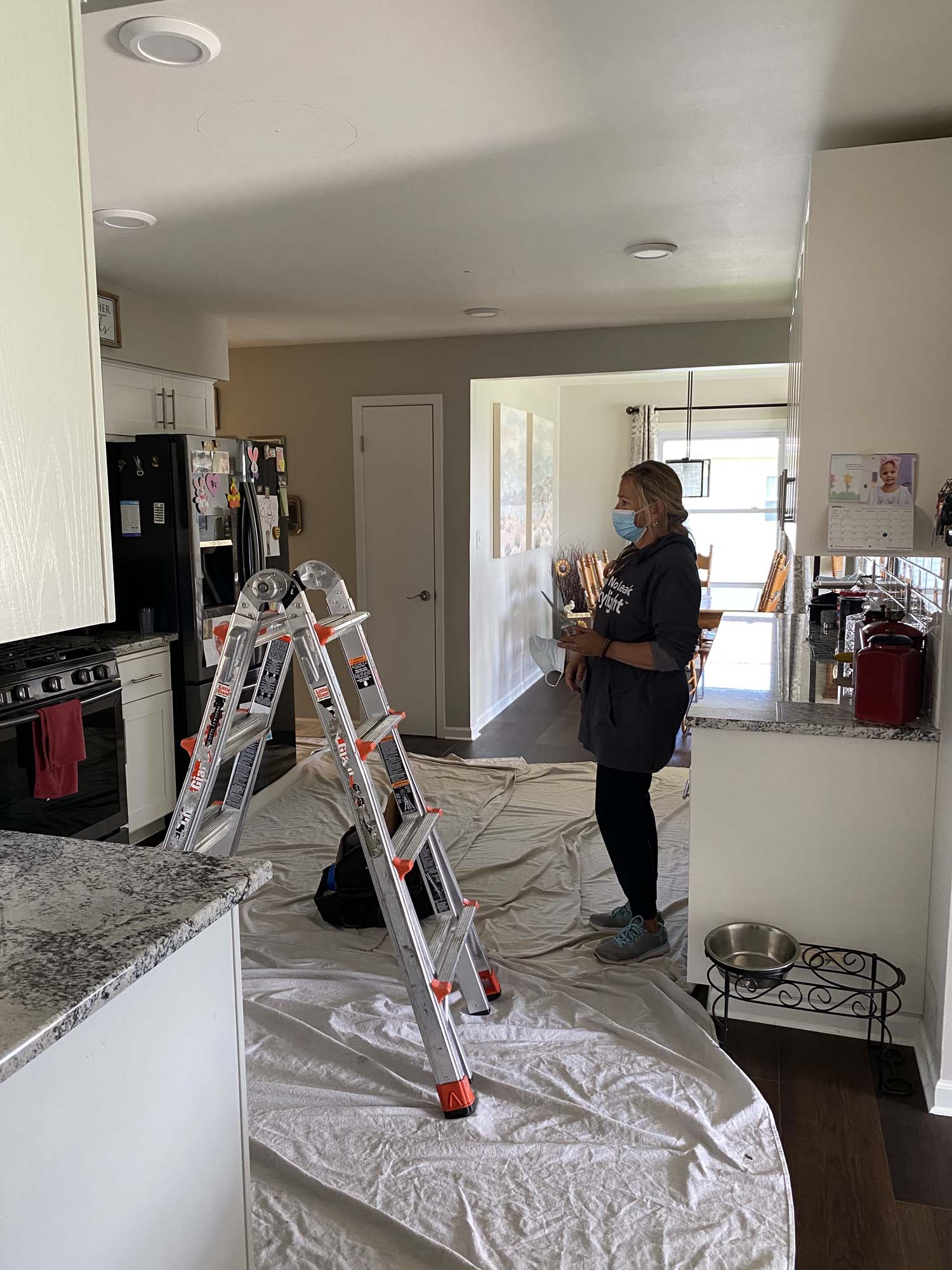 Team prepares a kitchen for two new skylights with drop-cloths, ladders, and tools