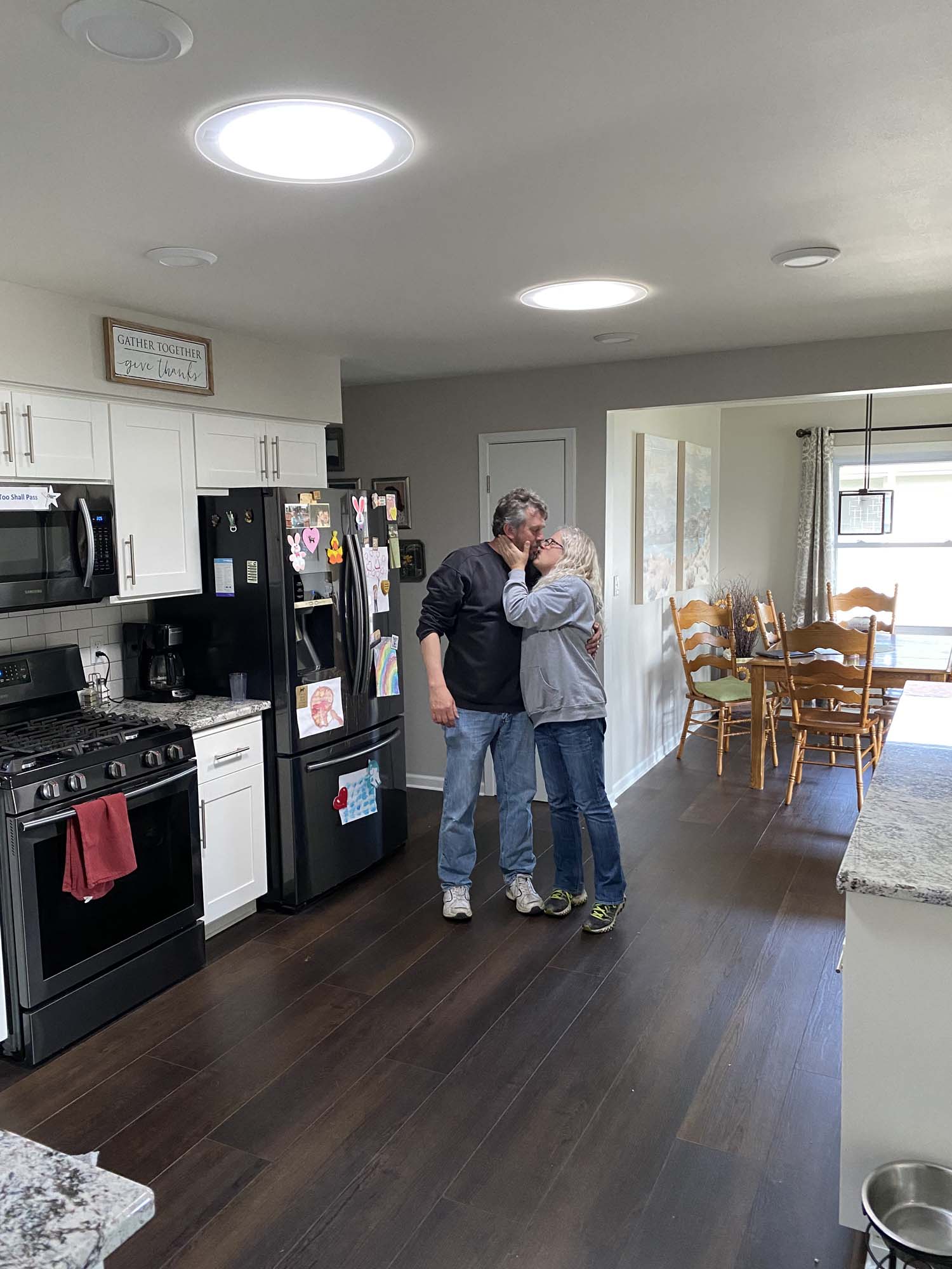 Husband & wife kisses underneath pair of new circular kitchen VELUX sun tunnel skylights installed by Wisconsin Sunlight Solutions.