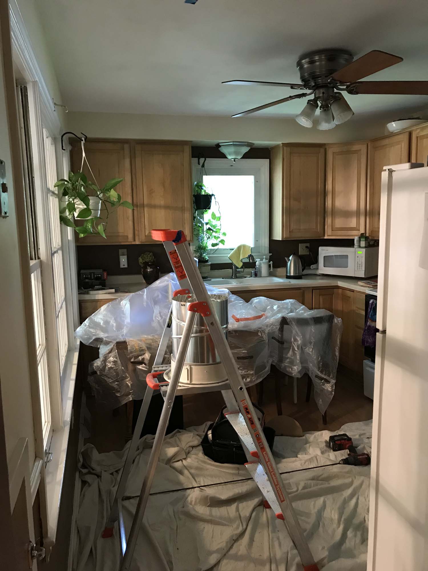 Employees prepare a kitchen for a new skylight ladders and drop-cloths